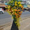 Kệ hoa hướng dương hồng cam và lan vàng trên chân đứng